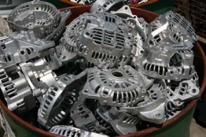 A pile of car alternators in a bucket ready to be recycled