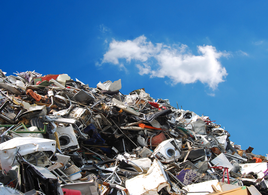 A large pile of computer waste with a blue sky and clouds in the background